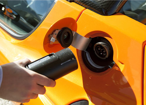 Close up of man charging an orange electric car