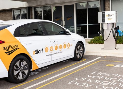 An electric car with sg fleet and e start branding in a parking space next to an electric charge point