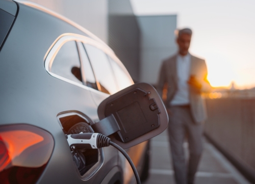 A businessman walking to his electric car